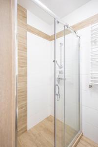 y baño con ducha acristalada y paredes blancas. en Apartament 106 Mari - Welle, en Grzybowo