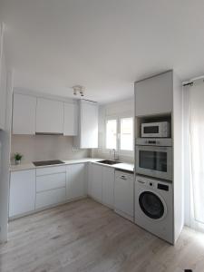 a kitchen with white cabinets and a washer and dryer at Aiguaneu S'Auguer in Blanes