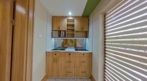 a small kitchen with wooden cabinets and a microwave at C. Apartments Annex in Abuja