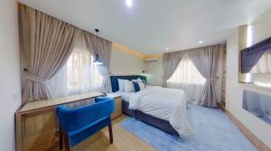 a bedroom with a bed and a desk and two windows at C. Apartments Annex in Abuja
