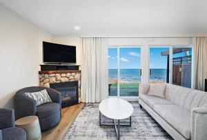 een woonkamer met een bank en een open haard en de oceaan bij Kingfisher Pacific Resort & Spa in Courtenay