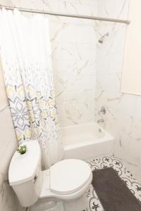 a white bathroom with a toilet and a bath tub at Elegant Modern 3-Bed Apt near NYC in Jersey City