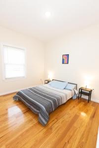 a bed in a white room with a wooden floor at Elegant Modern 3-Bed Apt near NYC in Jersey City