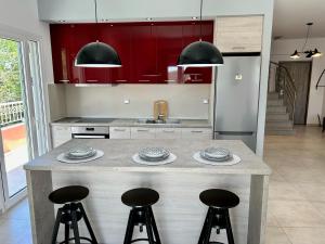 a kitchen with red cabinets and a counter with stools at Bridge House Corfu in Potamós