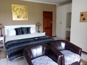 a bedroom with a bed and two leather chairs at Happy Jackal Guest House in Colchester