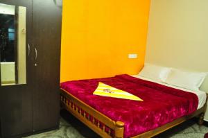 a bed with a red blanket and a yellow insignia on it at Seven Endue Cottages in Ooty