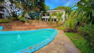 a swimming pool in front of a house at Silver Rock Hotel in Malindi