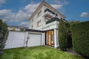 ein weißes Haus mit einer Garage und einem grünen Hof in der Unterkunft La Villa - Piscine / Karaoké / Jeux in Fontaine