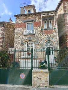een huis met een groene poort ervoor bij Rez de chaussée et 1er étage et jardin dans Maison individuelle in Enghien-les-Bains