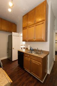 una cocina con armarios de madera y fregadero en Chic 3BR Hideaway mins from NYC, en Jersey City