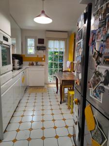 eine Küche mit einem Kühlschrank und einem Tisch darin in der Unterkunft Rez de chaussée et 1er étage et jardin dans Maison individuelle in Enghien-les-Bains
