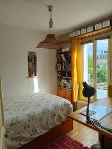 a bedroom with a bed and a large window at Rez de chaussée et 1er étage et jardin dans Maison individuelle in Enghien-les-Bains