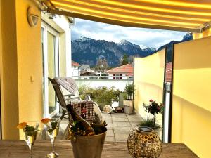 a balcony with a table and chairs and a view of mountains at Ferienwohnung-Königsschlösser in Füssen
