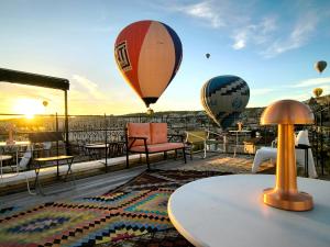 drie heteluchtballonnen vliegen in de lucht op een dak bij Karadut Cave Hotel in Goreme
