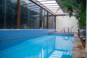 an indoor swimming pool with blue tile and glass walls at Prestige Manaus Hotel in Manaus