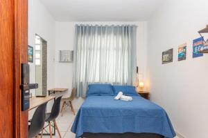 a bedroom with a blue bed and a desk at Novo e Confortável Studio no RJ/Lapa Circo Voador in Rio de Janeiro