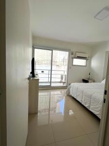Luminoso departamento en Villa Crespo في بوينس آيرس: غرفة نوم بيضاء بها سرير ونافذة