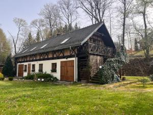 dom z dachem gambrel z trawnikiem w obiekcie Dom Gościnny Leniuchy w mieście Leśna