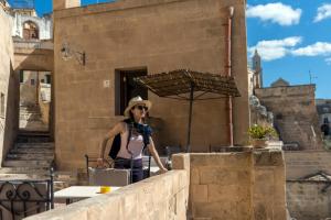 Una donna in piedi su un muro con un ombrello di Locanda Di San Martino Hotel & Thermae Romanae a Matera