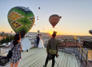 ギョレメにあるカラダット ケイヴ ホテルの甲板に立って熱気球を見る集団