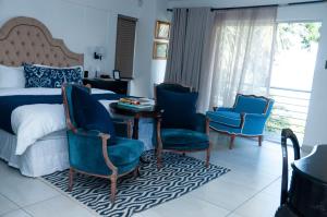 a bedroom with a bed and two chairs and a table at 129inHarties Lodge and SPA in Hartbeespoort