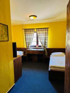 żółty pokój z 2 łóżkami i oknem w obiekcie Penzion Myslivna w mieście Velký Újezd