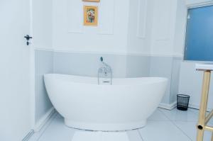 a white bathroom with a large white bath tub at 129inHarties Lodge and SPA in Hartbeespoort +19 photos