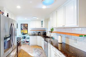 una cocina con armarios blancos y encimeras negras en Red Rocks Retreat en Englewood