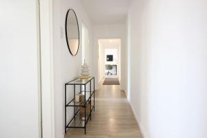 a hallway with white walls and a mirror on the wall at Blossfeld-Apartments XL-Ferienwohnung Jena Zentrum, 2 Schlafzimmer, W-Lan, Waschtrockner, Smart-TV in Jena
