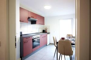 a kitchen with pink cabinets and a table with a dining room at Blossfeld-Apartments XL-Ferienwohnung Jena Zentrum, 2 Schlafzimmer, W-Lan, Waschtrockner, Smart-TV in Jena