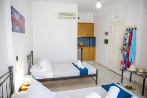 a living room with two beds and a kitchen at Pension St.George Rooms & Studios in Perivolos