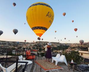 a woman is standing on a balcony with a hot air balloon at Karadut Cave Hotel in Goreme