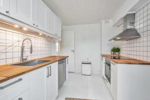 Biała kuchnia z białymi szafkami i zlewem w obiekcie Lund Apartment w mieście Kristiansand