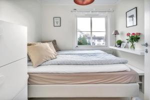 biała sypialnia z łóżkiem i oknem w obiekcie Lund Apartment w mieście Kristiansand