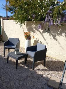 three chairs and a table and a vase with flowers at Studio avec Jardin et Parking Privés in Bormes-les-Mimosas