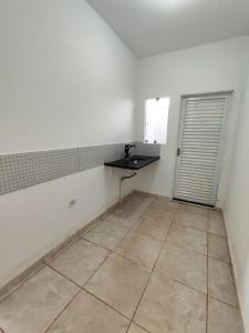 a white kitchen with a sink and a tiled floor at Loft Famíliar Br/Aeroporto 22 in Uberlândia