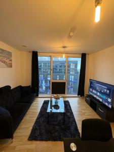 a living room with a couch and a tv at Spacious 2 Bedrooms Apartment In Stratford in London