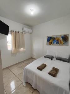 a white room with a bed with two towels on it at Loft Famíliar Br/Aeroporto 22 in Uberlândia