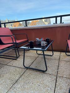 a coffee table on a balcony with two mugs on it at Appartement cosy vue port in Dives-sur-Mer