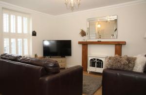 a living room with leather furniture and a flat screen tv at The Cosy Cottage Retreat! Perfect for Contractors, Relocators, Getaway in Llantrisant