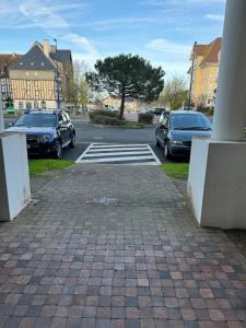 a parking lot with parked cars and a crosswalk at Escapade Romantique- Vue Port et Balcon Ensoleillé in Dives-sur-Mer