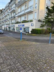 a building with a car parked in front of a street at Escapade Romantique- Vue Port et Balcon Ensoleillé in Dives-sur-Mer