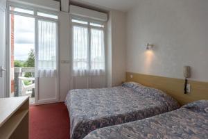 a hotel room with two beds and a balcony at Hôtel Montfort in Lourdes