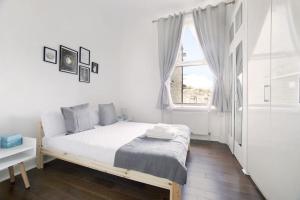 a white bedroom with a bed and a window at Apartment with garden 4 stop to Holland Park in London