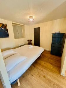 a bedroom with a large white bed and a dresser at Studio Liberté en centre-ville in Bourgoin