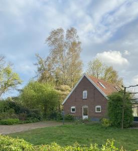 ein rotes Backsteinhaus mit Bäumen im Hintergrund in der Unterkunft Vakantiehuis De Fiere - op erf wijngaard De Fiere Wijnakker in Zutphen