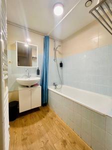 La salle de bains est pourvue d'un lavabo et d'une baignoire. dans l'établissement Studio Liberté en centre-ville, à Bourgoin-Jallieu