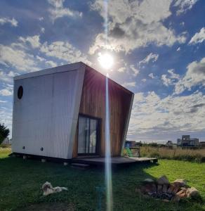 une petite maison sur un champ avec le soleil dans le ciel dans l'établissement AMARRA Camet Norte, à Santa Clara del Mar