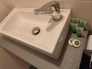 lavabo blanco en un baño con tazas verdes en una encimera en Spasmata Apartments no cooking en Minia