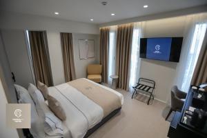 una camera con un grande letto e una TV di Central Inn Hotel a Tirana
